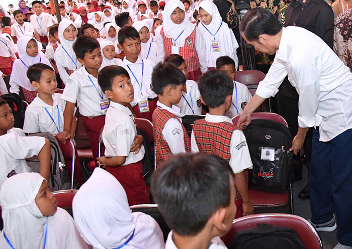 Presiden pun membagikan perlengkapan sekolah kepada para siswa.