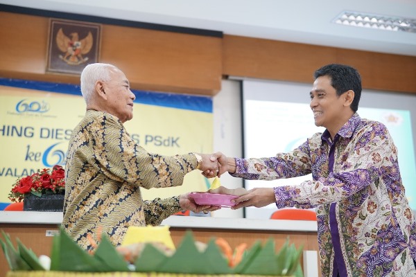Dosen senior PSdK, Drs Pratikto Prawirodiwarno memberikan potongan tumpeng  kepada Ketua Departemen PSdK, Dr. Krisdyatmiko (Foto Taufiq Hakim)