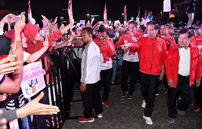 Presiden Joko Widodo dan Wakil Presiden Jusuf Kalla berjalan menuju panggung seraya berinteraksi dengan pengunjung yang menghadiri Countdown to Asian Games 2018 di Lapangan Monas, Jakarta Pusat.