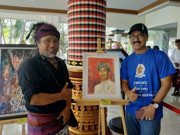 Salah satu lukisan wajah Presiden Jokowi yang dipamerkan, hari ini Kamis (14/11/2019) sudah ada yang membeli sebelum Pameran dibuka. Foto: Anton Mart (kanan) dan Ketut (kiri) sedang berpose bersama lukisan wajah Presiden Jokowi. Foto : Taufiq Hakim/KAGAMA